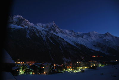 Scenic view of illuminated mountains against blue sky at night