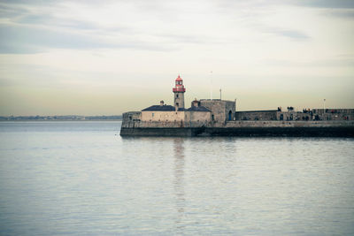 Lighthouse by sea against sky