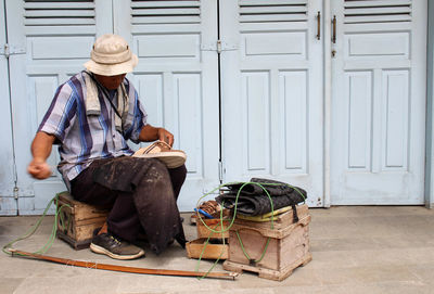 Full length of man sitting by door