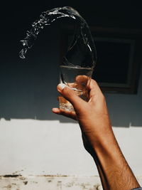 Cropped image of hand holding glass against blurred background