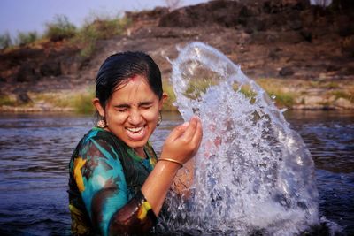 Portrait of happy boy splashing water in river