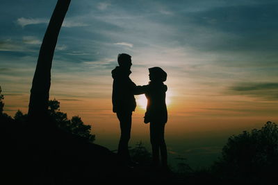 Silhouette men standing against sky during sunset