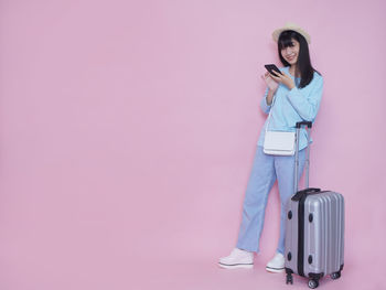 Full length of woman standing against pink background