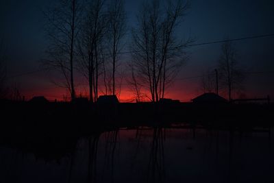 Reflection of silhouette trees in lake at sunset