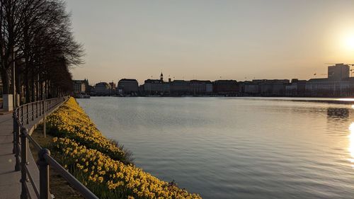 River by buildings against sky during sunset