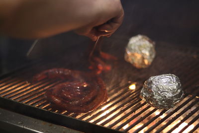 Cropped image of person hand on barbecue grill