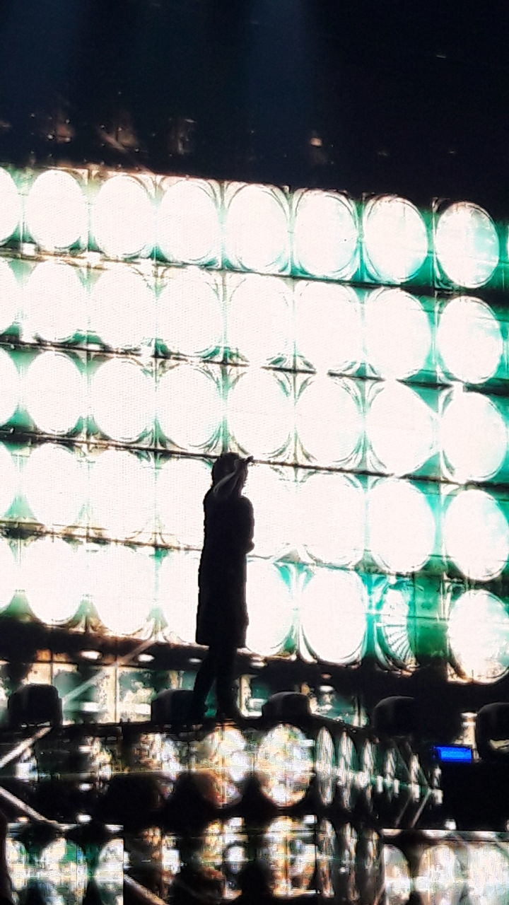 MAN STANDING BY FENCE AGAINST SKY SEEN THROUGH CHAINLINK