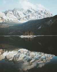 Scenic view of lake by snowcapped mountains against sky