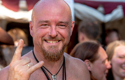 Close-up portrait of shirtless man gesturing horn sign during concert