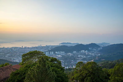 High angle view of buildings and trees against sky at sunset