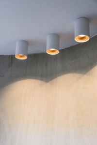From below of similar creative spotlight lamps hanging from white ceiling in modern room in apartment