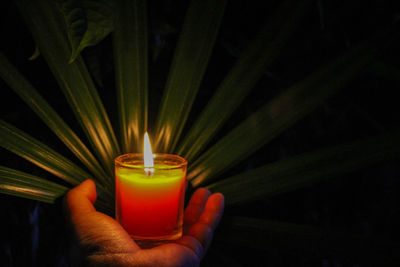 Close-up of hand holding lit candle