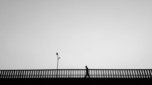 Low angle view of man walking on bridge against sky