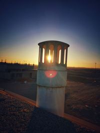 Close-up of illuminated lamp at beach against sky during sunset