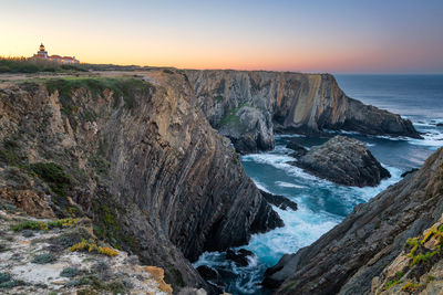 Scenic view of rocks in sea against sky during sunset