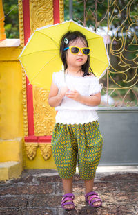 Girl wearing sunglasses standing against metal gate