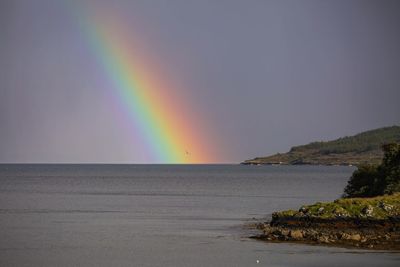 Scenic view of rainbow over sea against sky