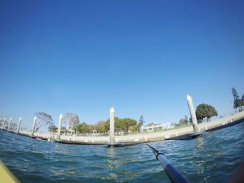 Boats in harbor against clear blue sky
