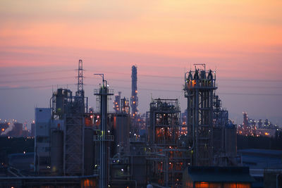 Illuminated factory against sky during sunset