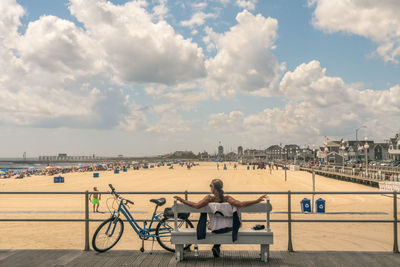 People sitting on seat in city against sky