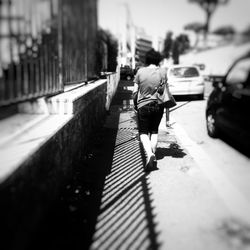 Rear view of man walking on sidewalk