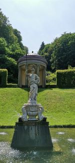 Statue by fountain in park against sky