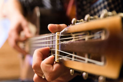 Cropped image of person playing guitar at home