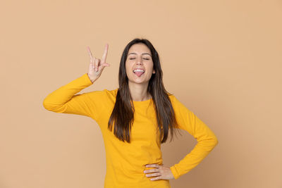 Young woman standing against yellow background