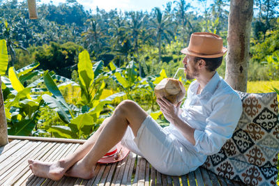 Midsection of man sitting on seat at park
