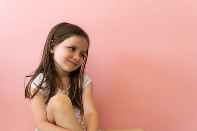 Portrait of smiling girl against pink background