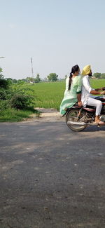 People riding motorcycle on road against sky