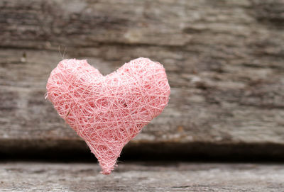 Close-up of heart shape threads against plank