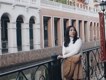 Portrait of woman standing against railing