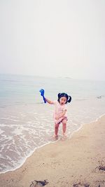 Portrait of boy standing on beach against clear sky