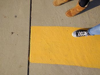 Low section of man standing on yellow shoes