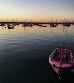 Sailboats moored in lake against sky during sunset