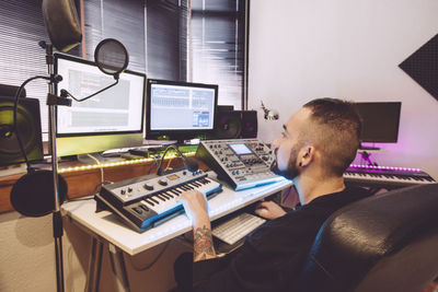 Man using computer and piano on table