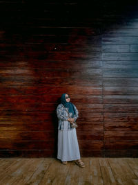 Rear view of woman standing in wood wall