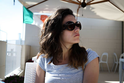 Young woman wearing sunglasses on chair in cafe