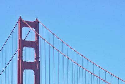 Low angle view of suspension bridge against clear blue sky