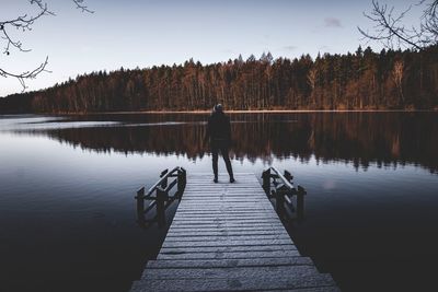 Rear view of man standing by lake against sky