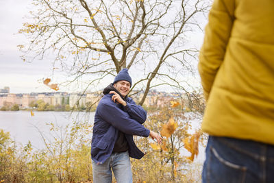 Happy young man throwing autumn leaves