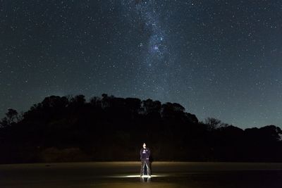 Man standing on field against starry sky at night