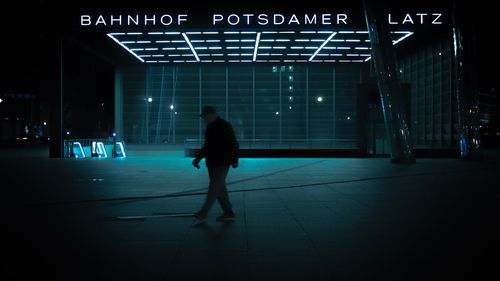 Full length rear view of silhouette man walking in illuminated city