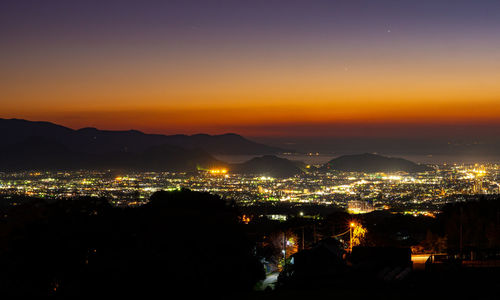 High angle view of illuminated city against sky at night