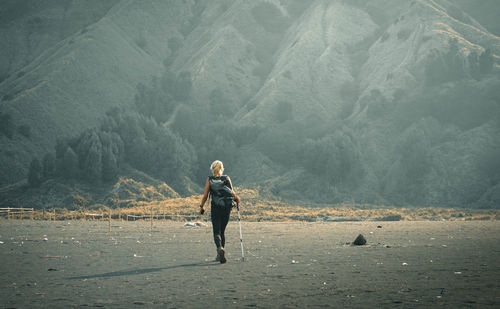 Full length of woman walking on land against mountains