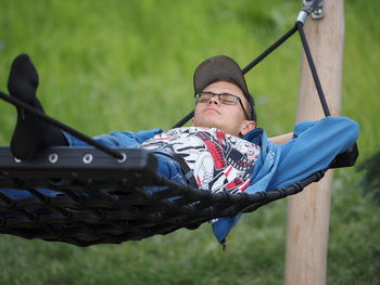 A young man is lying on a hammock in a park or garden outdoors. high quality photo