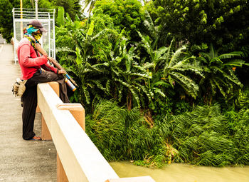 Side view of woman using mobile phone on tree