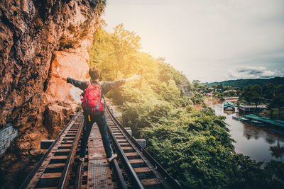 Rear view of woman on railroad tracks against sky
