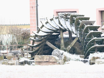 Built structure on field by house against clear sky during winter